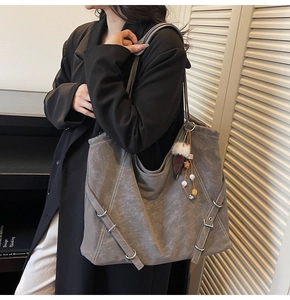 Détail du sac cabas en daim gris avec boucle décorative et breloque en peluche