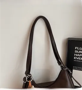 Detail of the comfortable leather handle and silver metal ring on dark brown shoulder bag