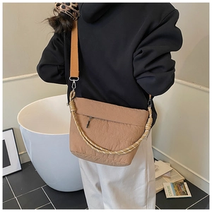 Detail showing khaki nylon bucket bag with woven handle and adjustable wide canvas strap