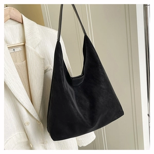 Detailed close-up of a minimalist black matte tote bag hanging on a white suit jacket