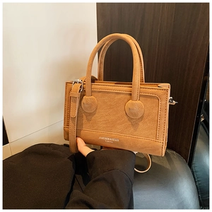 Detail shot of the matte textured brown handbag showing silver lettering and fine stitching