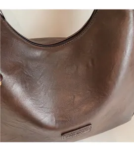 Close-up of deep brown vintage leather texture and embossed logo on a large tote bag