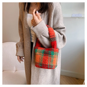 Detail of plush faux shearling bucket bag with orange and green plaid pattern