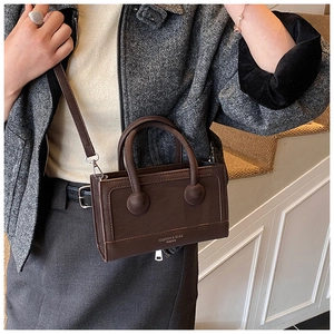 Close-up of dark brown vintage handbag featuring unique spherical handle accents and golden logo