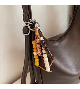 Close-up of colorful wooden bead pendant with metal ring on minimalist PU leather bag