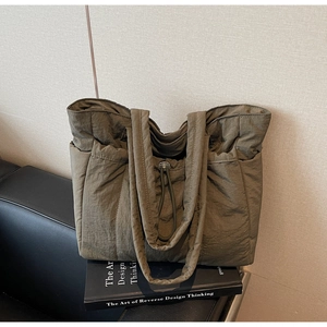 Detail of drawstring closure and side pockets on olive green padded nylon tote bag