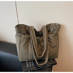 Detail of olive green quilted tote bag showing nylon texture and drawstring closure