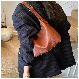 Braune Hobo-Tasche mit Litschimuster, kombiniert mit dunklem Blazer in minimalistischer Szene