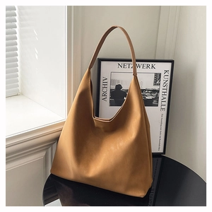 Minimalist tan leather tote bag shown on a black table with stylish interior decor