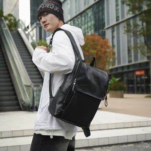Chic black leather backpack with flap and metal zipper shown on a white coat model