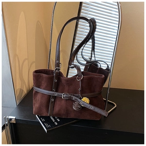Detail of dark brown suede tote bag featuring adjustable leather straps and floral charms