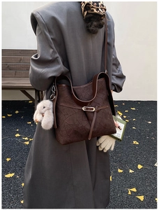 Detail of dark brown pleated hobo bag featuring a cute plush bunny charm on the side