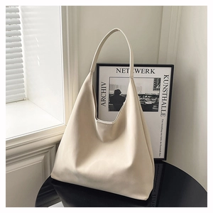 Minimalist beige hobo tote bag in smooth faux leather on a stylish black desk