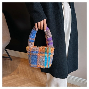Close-up of a colorful checkered plush tote bag held by a person in a minimalist setting