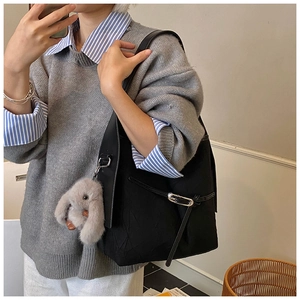 Detail of black large capacity shoulder bag with silver buckle and plush rabbit charm