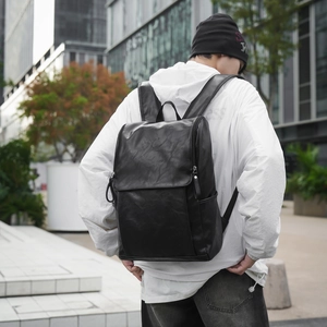 Detailed texture of black synthetic leather on a large capacity flap-top casual backpack