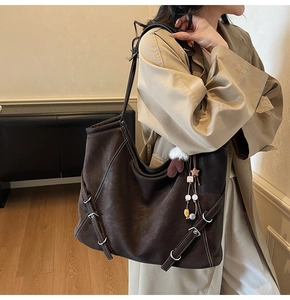Détail d'un grand sac cabas marron foncé avec boucles latérales réglables