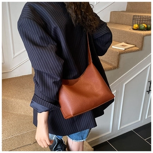 Close-up of brown litchi pattern leather hobo bag on shoulder with natural drape effect