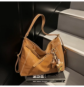 Close-up of brown oversized tote bag with white stitching and cute bear keychain