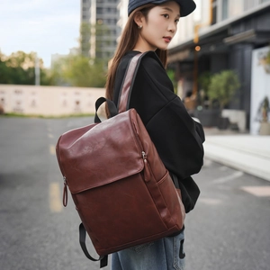 Detailed side view of a brown leather backpack worn by a model in an urban outdoor setting