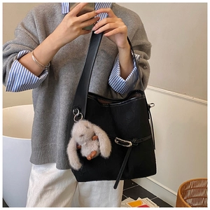 Detail of black faux leather tote bag with rabbit plush charm and metal ring strap
