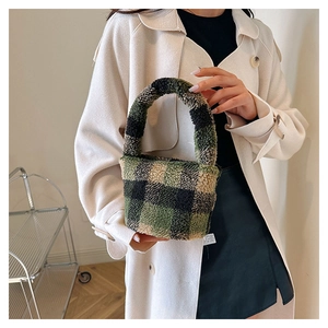 Detail of green and black plaid fuzzy bucket bag held by a model in a long coat