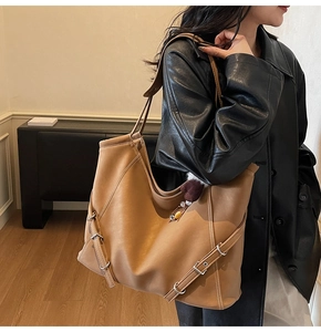 Sac fourre-tout marron en similicuir avec boucles latérales porté à l'épaule par un mannequin