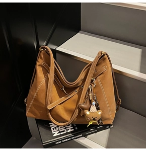 Detail of vintage brown tote bag with contrast stitching and bear charm on stairs