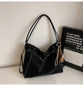 Detail of black leather tote bag with white contrast stitching and gold-tone hardware