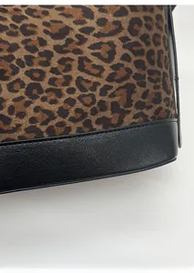 Detail of leopard print suede fabric with durable black leather edge on the tote bag base