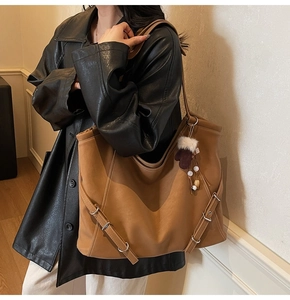 Détail d'un sac cabas en cuir marron avec boucles en métal et pompon décoratif doux