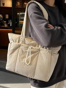 Quilted beige puffer tote bag with drawstring pockets and padded straps for commuting