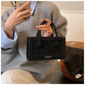 Detail of a minimalist black matte handbag with dual top handles for daily commuting