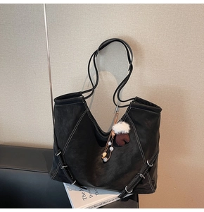 Détail d'un sac cabas noir avec coutures contrastées blanches et charm en peluche