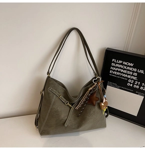 Macro detail of olive green leather hobo bag with vintage stitching and star bear charms