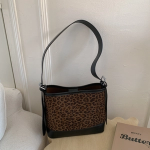 Detail of leopard print tote bag with black leather straps and silver metal buckle