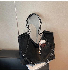 Détail d'un grand sac cabas noir avec surpiqûres contrastées et pendentif gant en peluche