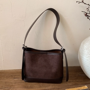 Close-up of deep brown suede bucket bag with leather trim and adjustable metal buckle