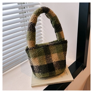 Close-up of fuzzy green checkerboard plush bucket bag on a minimalist book prop