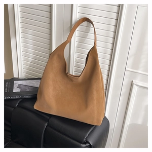 Detail of a brown matte faux leather hobo bag on a sofa showing large capacity and texture