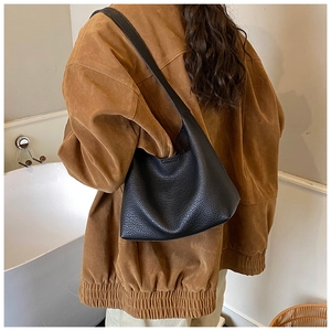 Nahaufnahme der schwarzen Hobo-Tasche aus genarbtem Leder, getragen von einem Model