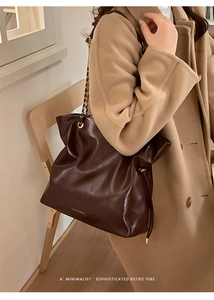 Detail of vintage coffee leather tote bag with gold chain strap and drawstring closure