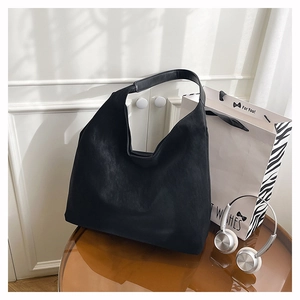 Close-up of minimalist black hobo tote bag in matte synthetic leather with wide strap