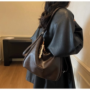 Macro shot of dark brown oversized tote bag with wooden bead charm and soft texture