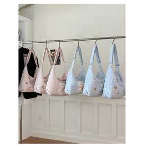 Détails de la texture matelassée en cœur et broderie chiot sur des sacs cabas souples