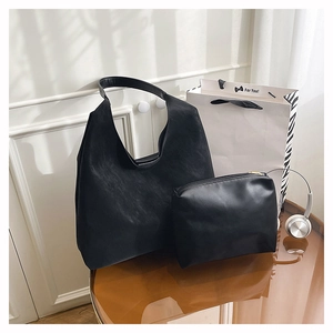 Minimalist black tote bag set with a matching pouch on a sleek reflective surface