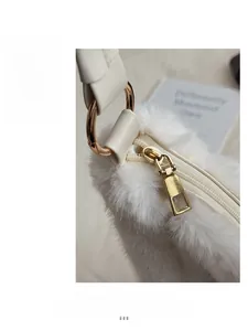 Close-up of golden zipper and hardware on white plush bucket tote bag detail