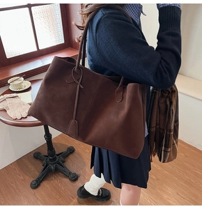 Macro detail of dark brown suede tote bag with minimalist leather tag and texture