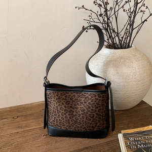 Macro shot of leopard print texture and black leather stitching on a vintage tote bag