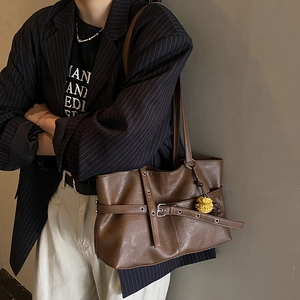 Detailed view of dark brown faux leather tote bag with yellow pompom and metal buckle